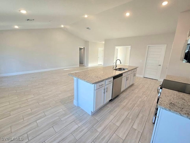 kitchen with wood finish floors, a sink, appliances with stainless steel finishes, light stone countertops, and vaulted ceiling