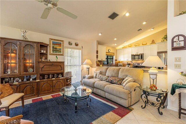 tiled living room with ceiling fan and vaulted ceiling