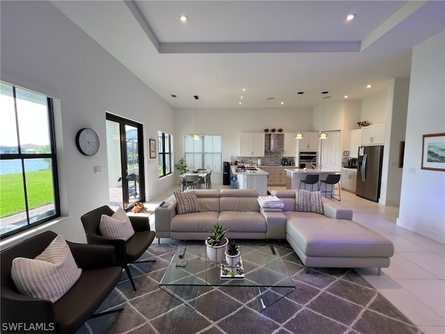 living room featuring plenty of natural light, tile flooring, and a raised ceiling