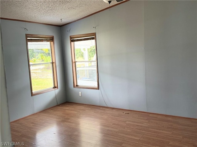 unfurnished room featuring a textured ceiling, light hardwood / wood-style flooring, and crown molding