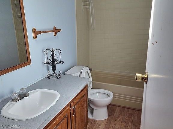 full bathroom featuring wood-type flooring, toilet, vanity, and shower / tub combination