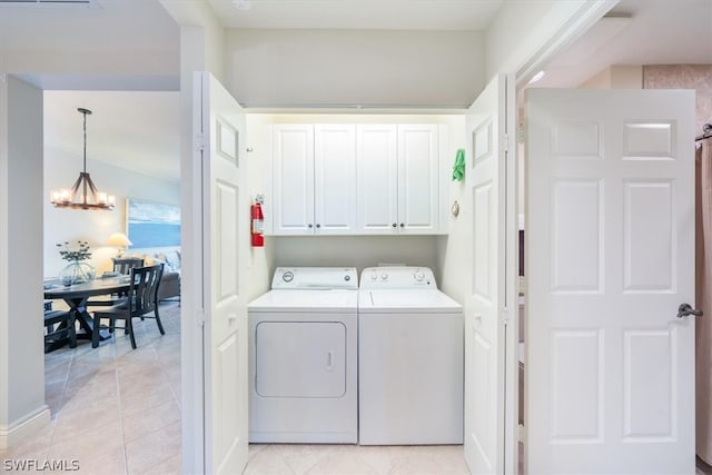 clothes washing area featuring a notable chandelier, independent washer and dryer, light tile floors, and cabinets