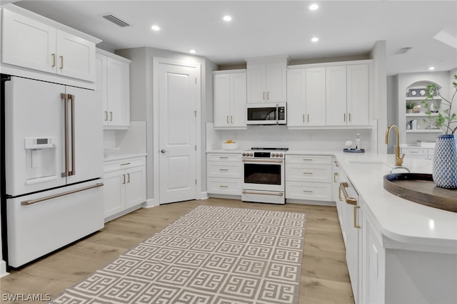 kitchen with white cabinets, backsplash, light wood-type flooring, sink, and white appliances