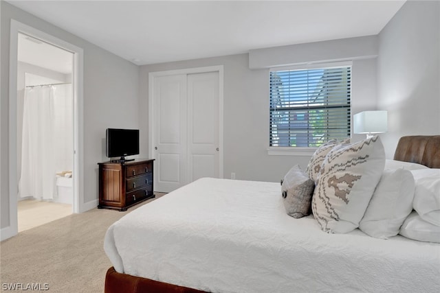 bedroom featuring a closet, ensuite bathroom, and carpet flooring