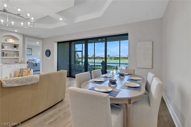 dining area featuring built in features, an inviting chandelier, and light wood-type flooring