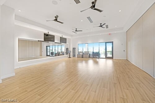 unfurnished living room featuring a raised ceiling and light hardwood / wood-style flooring