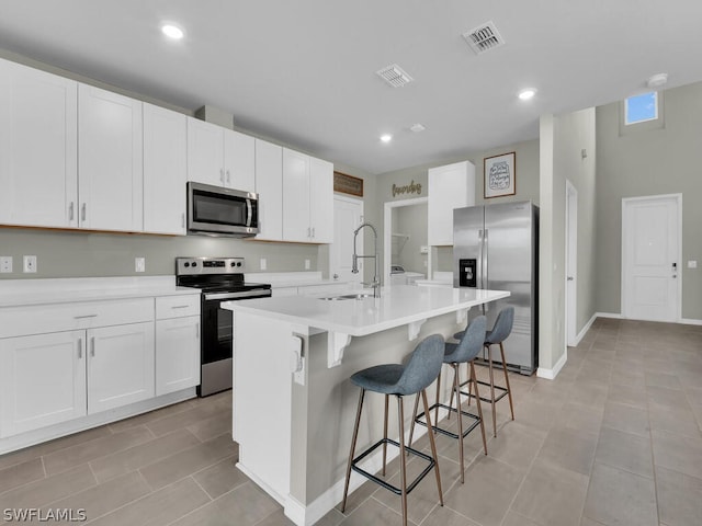 kitchen featuring sink, white cabinets, a center island with sink, and appliances with stainless steel finishes