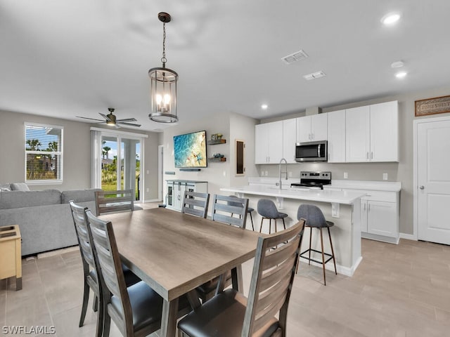 tiled dining space featuring ceiling fan with notable chandelier and sink