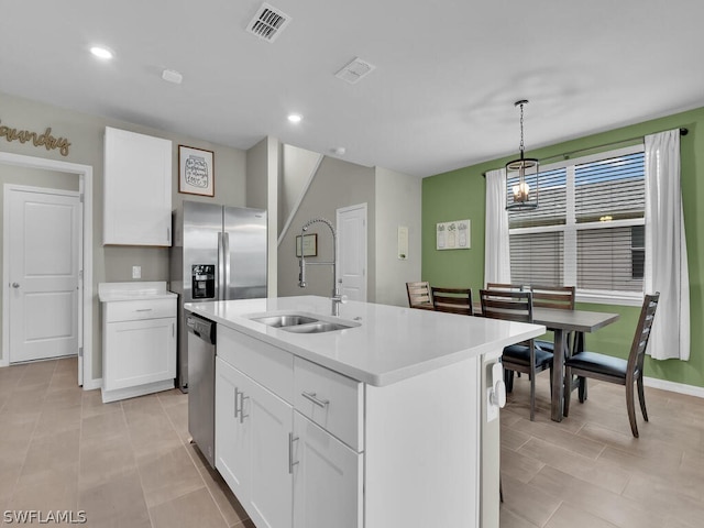 kitchen featuring decorative light fixtures, light tile flooring, stainless steel appliances, a kitchen island with sink, and white cabinetry