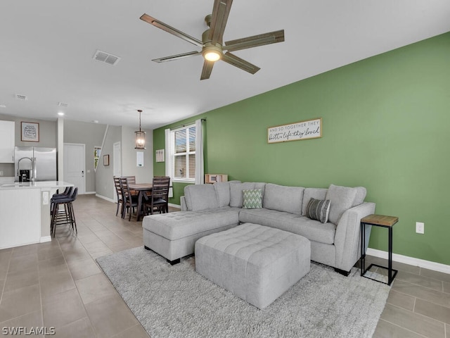 tiled living room featuring ceiling fan with notable chandelier