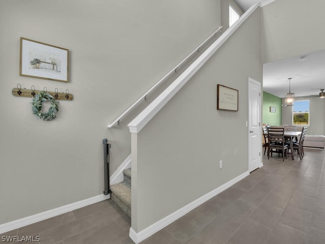 stairs with a towering ceiling and dark tile floors