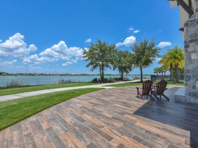 wooden terrace with a water view and a yard