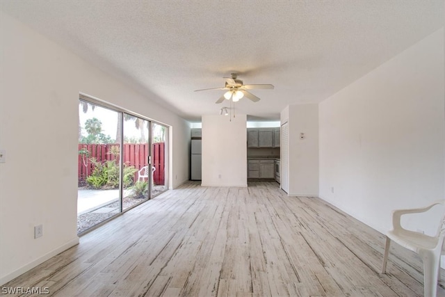 unfurnished living room featuring ceiling fan, a textured ceiling, and light wood-type flooring