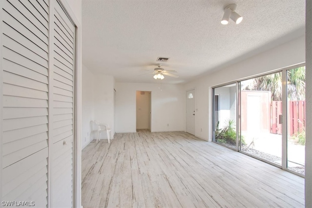 unfurnished room featuring light hardwood / wood-style floors, ceiling fan, and a textured ceiling