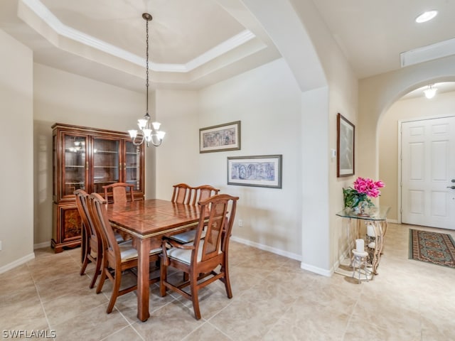 tiled dining area featuring a raised ceiling and a chandelier