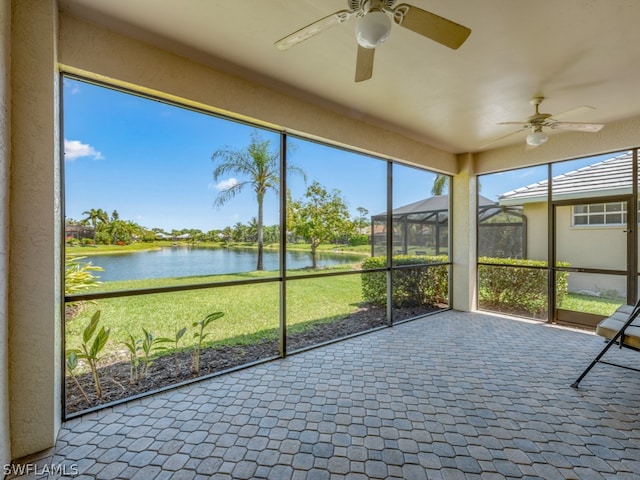 unfurnished sunroom featuring plenty of natural light, a water view, and ceiling fan