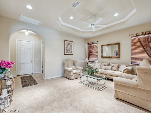 living room featuring ceiling fan, a tray ceiling, and light tile patterned floors