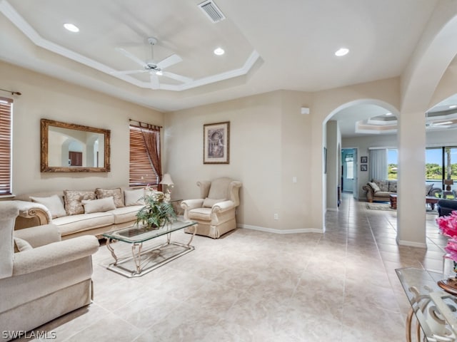 living room with a tray ceiling, tile patterned flooring, and ceiling fan