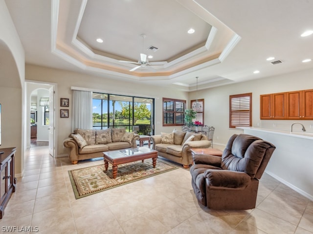 tiled living room with sink, ceiling fan, and a tray ceiling