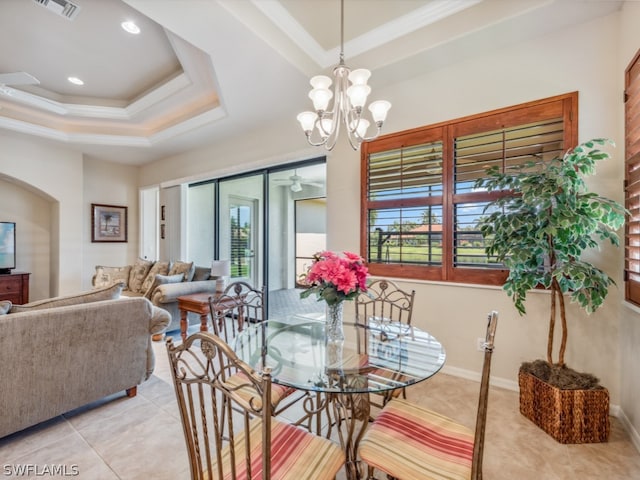 dining room featuring ceiling fan with notable chandelier, tile patterned flooring, and a tray ceiling