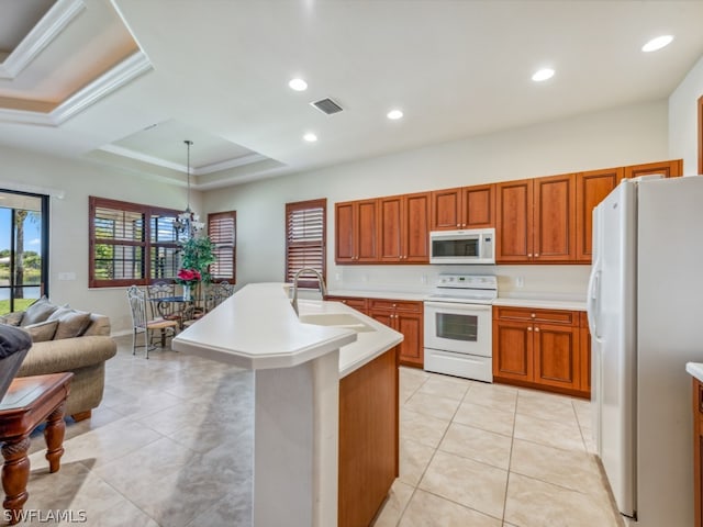 kitchen with pendant lighting, an island with sink, white appliances, sink, and a raised ceiling