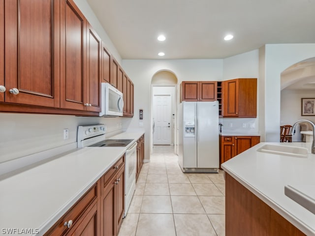 kitchen featuring sink, light tile patterned flooring, and white appliances