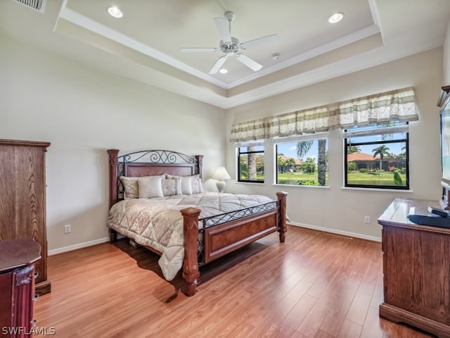 bedroom featuring ceiling fan, ornamental molding, a tray ceiling, and hardwood / wood-style floors