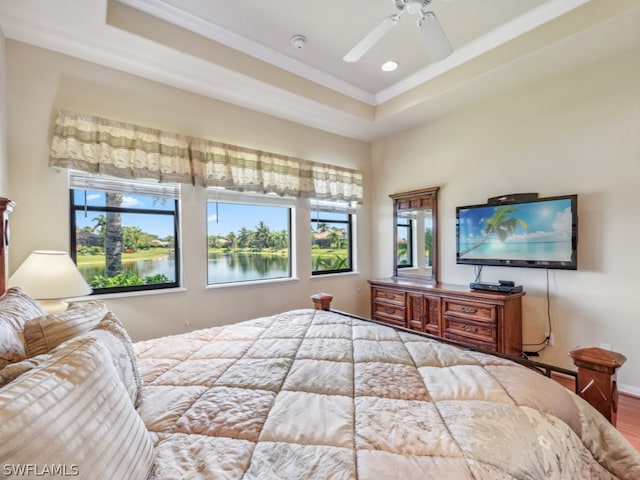 bedroom featuring wood-type flooring, ceiling fan, a raised ceiling, and ornamental molding