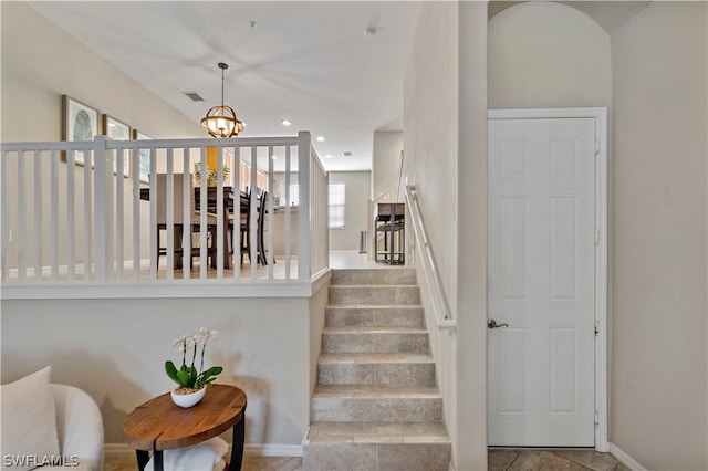 stairs featuring tile flooring, a healthy amount of sunlight, and a chandelier