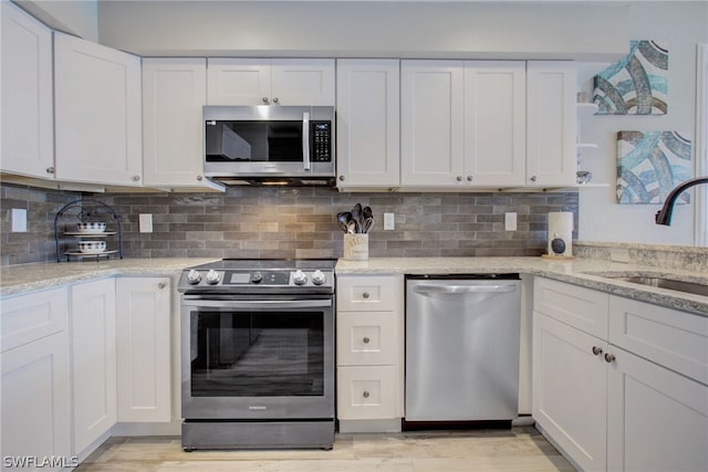 kitchen featuring appliances with stainless steel finishes, a sink, white cabinetry, and tasteful backsplash