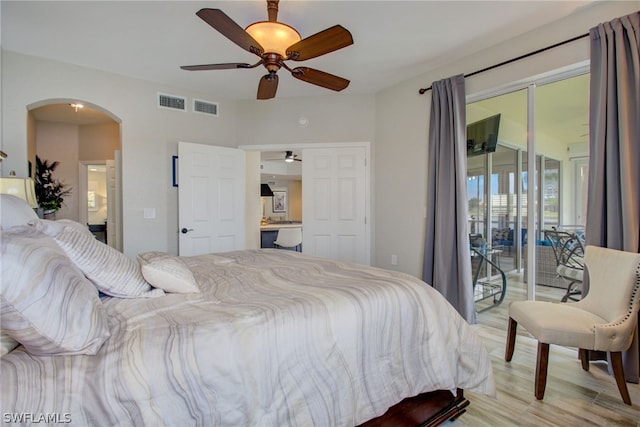 bedroom featuring arched walkways, access to outside, light wood-style flooring, and visible vents