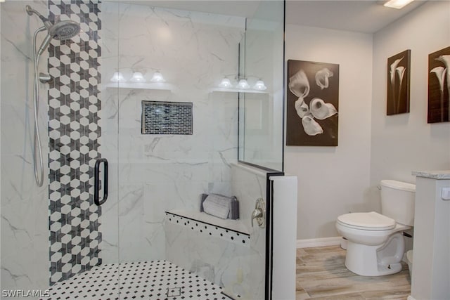 bathroom with a stall shower, baseboards, toilet, and wood finished floors