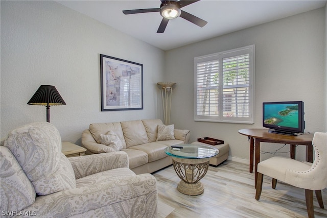 living room with a ceiling fan, baseboards, and wood finished floors