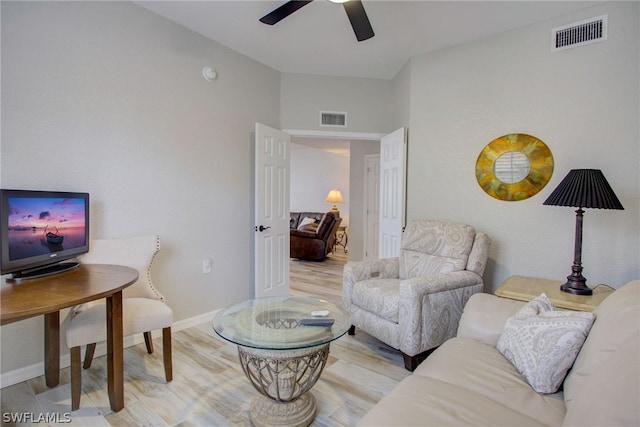 living area with ceiling fan, wood finished floors, visible vents, and baseboards