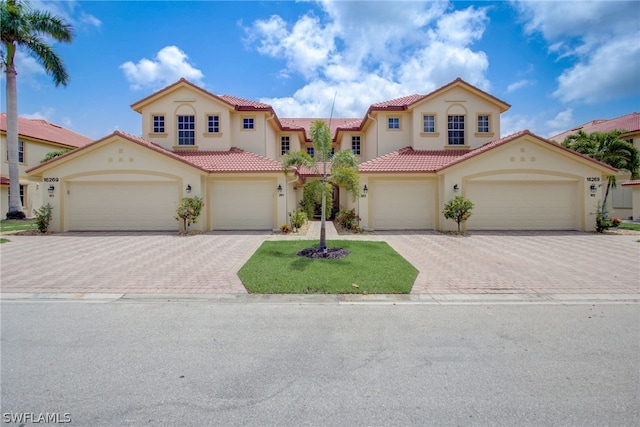 mediterranean / spanish-style house with a tiled roof, decorative driveway, and stucco siding