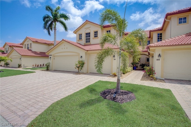 mediterranean / spanish-style home with a garage, a tile roof, decorative driveway, stucco siding, and a front yard