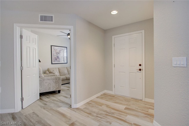 corridor featuring visible vents, baseboards, and wood finished floors