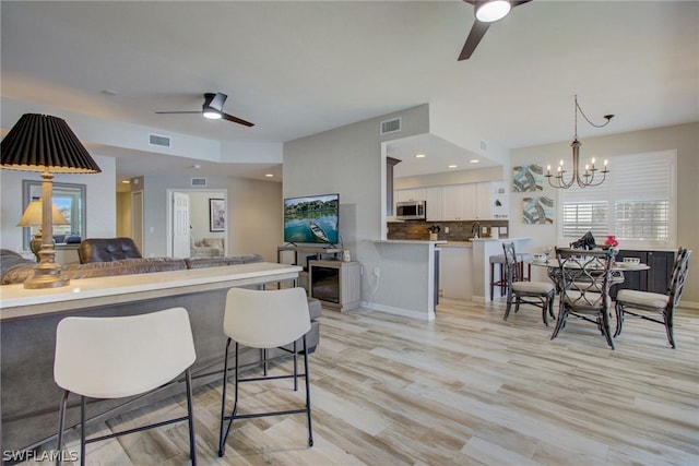 kitchen featuring ceiling fan with notable chandelier, stainless steel microwave, visible vents, and white cabinetry