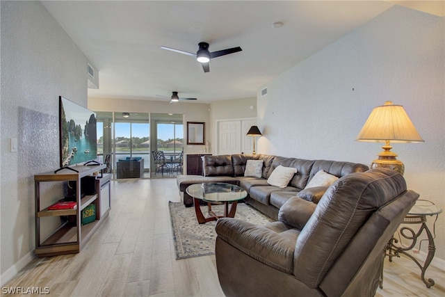 living area with light wood finished floors, ceiling fan, and baseboards