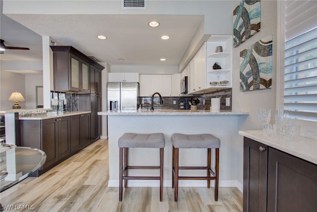 kitchen with stainless steel appliances, light wood-type flooring, dark brown cabinetry, and open shelves