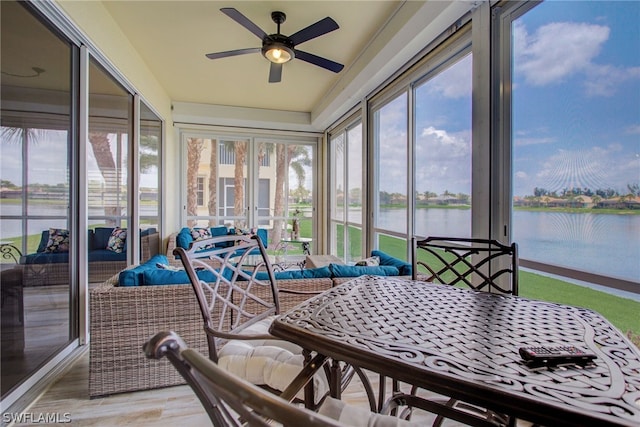 sunroom featuring a water view and a ceiling fan