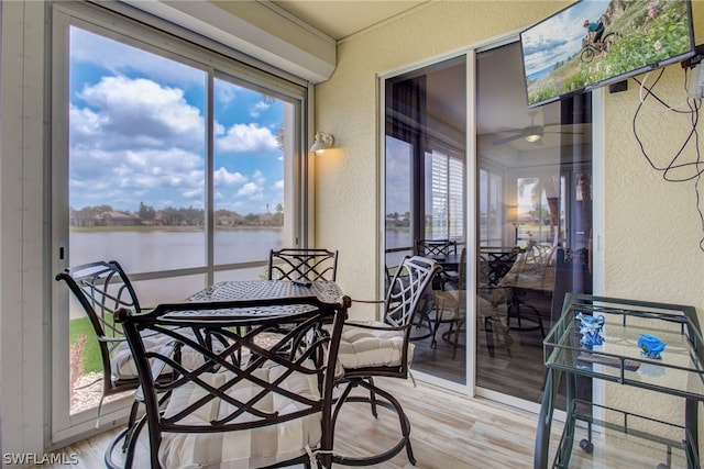 sunroom / solarium featuring a water view and a ceiling fan