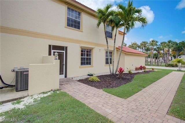 view of home's exterior with a yard, cooling unit, and stucco siding