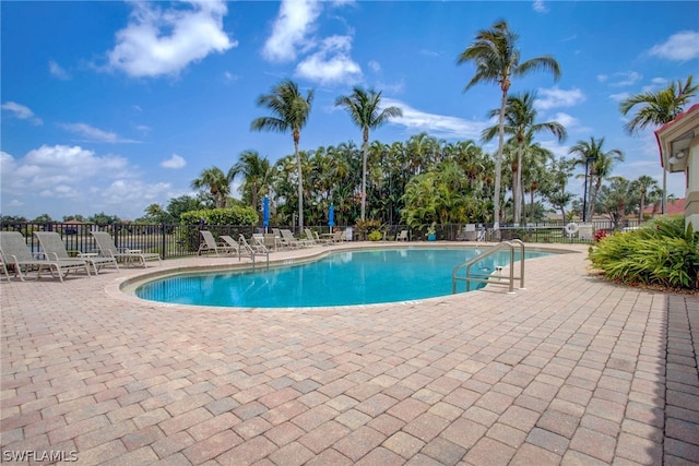 pool with a patio area and fence