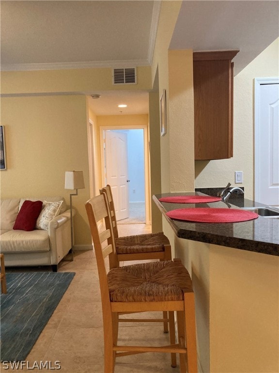 dining space with light tile patterned floors, visible vents, and crown molding