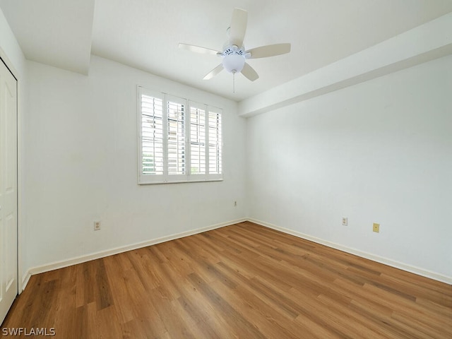 spare room with a ceiling fan, light wood-style flooring, and baseboards