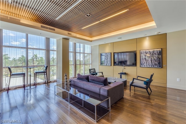 living room featuring dark hardwood / wood-style floors, a raised ceiling, and expansive windows