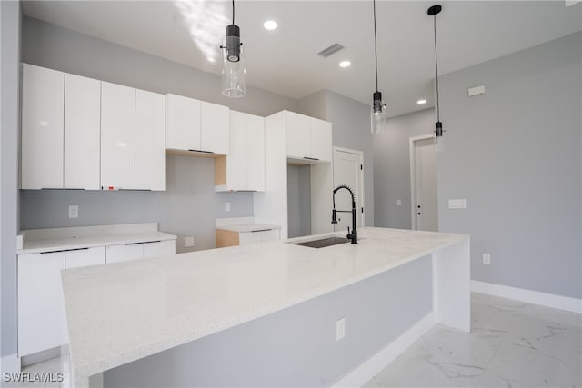 kitchen with white cabinets, a kitchen island with sink, and decorative light fixtures