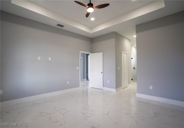 spare room featuring ceiling fan and a raised ceiling