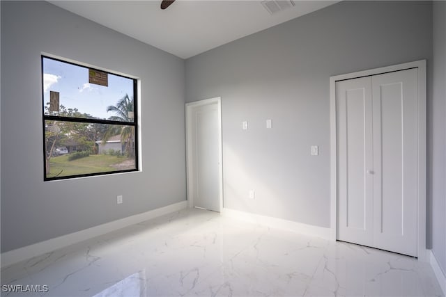 unfurnished bedroom with ceiling fan and a closet